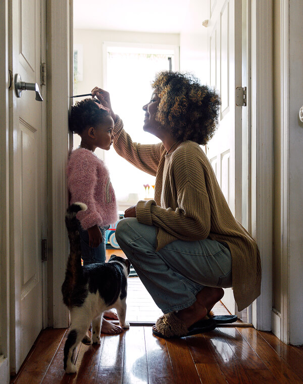 Mother and daughter checking height on door frame.