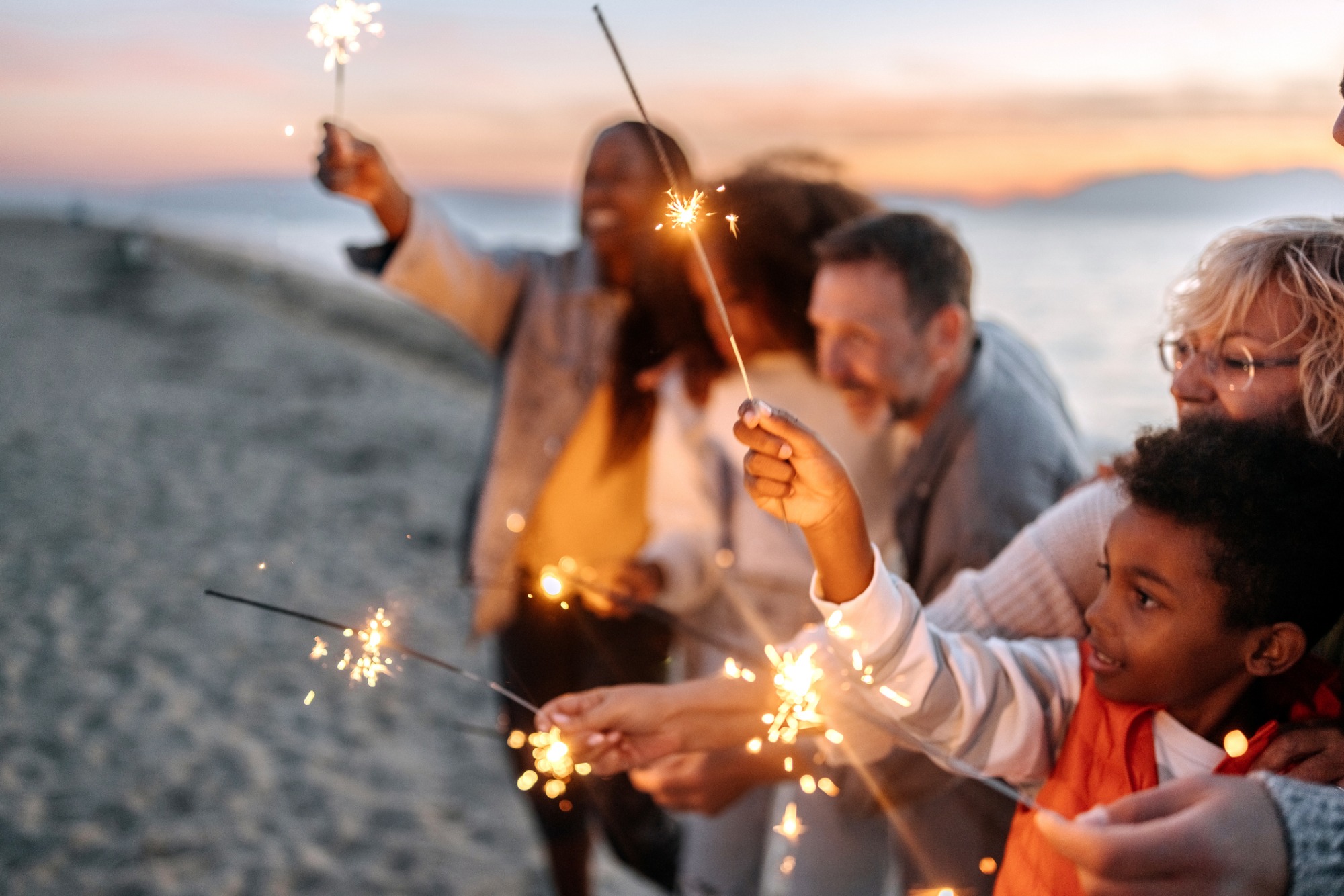 Group of people on a beach with lit sparklers