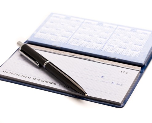 Open checkbook with a pen laying across it